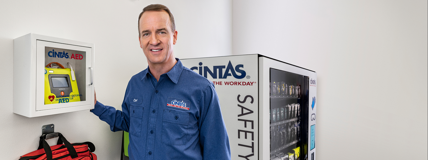 cintas service representative standing in front of a first aid and safety wall
