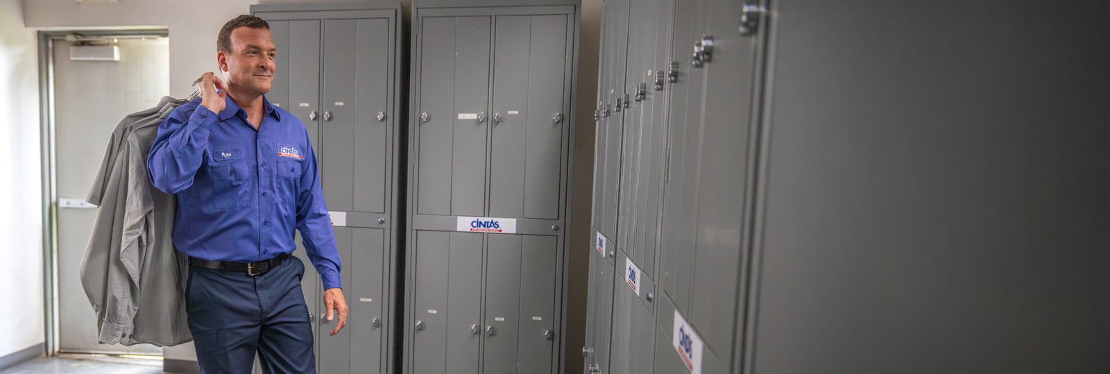 cintas service representative carrying cleaned garments into a locker room for delivery