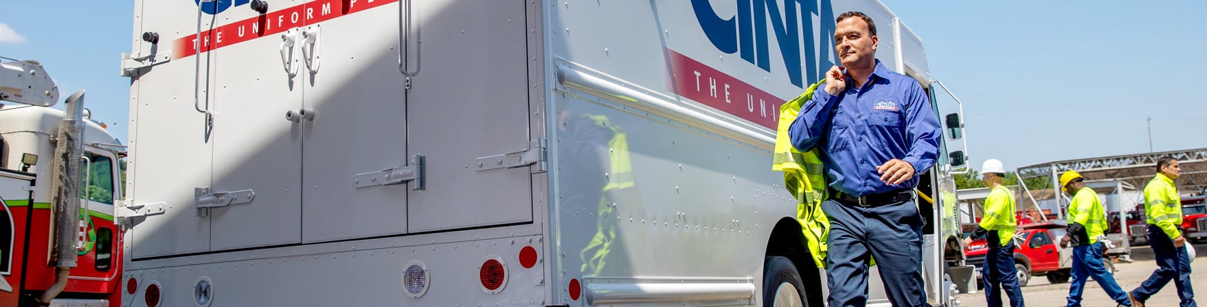 cintas service representative carrying cleaned visibility garments in front of the service truck