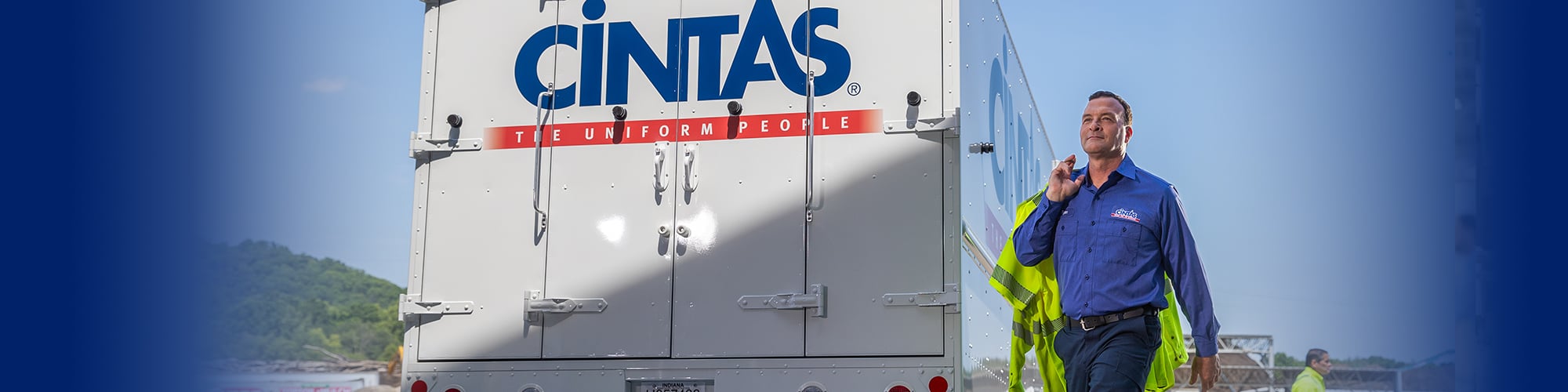 Cintas representative carrying uniforms in front of a cintas truck